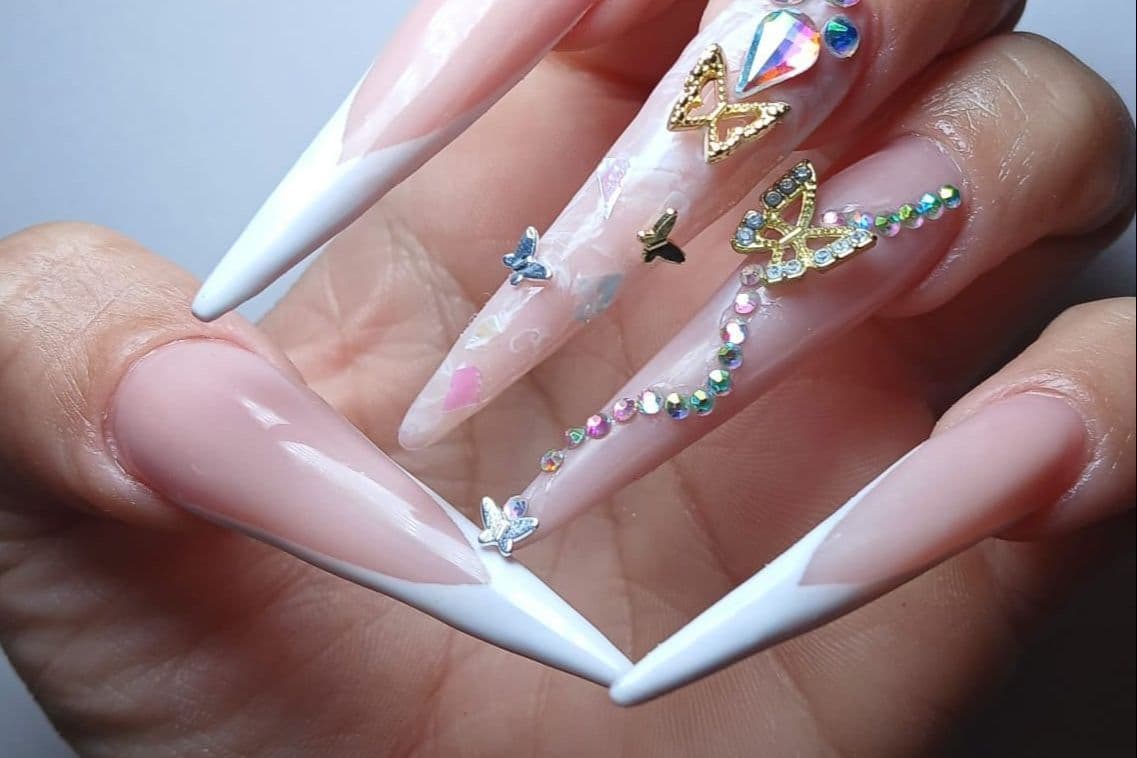 Stiletto nails with white tips, colorful crystals and gold butterflies