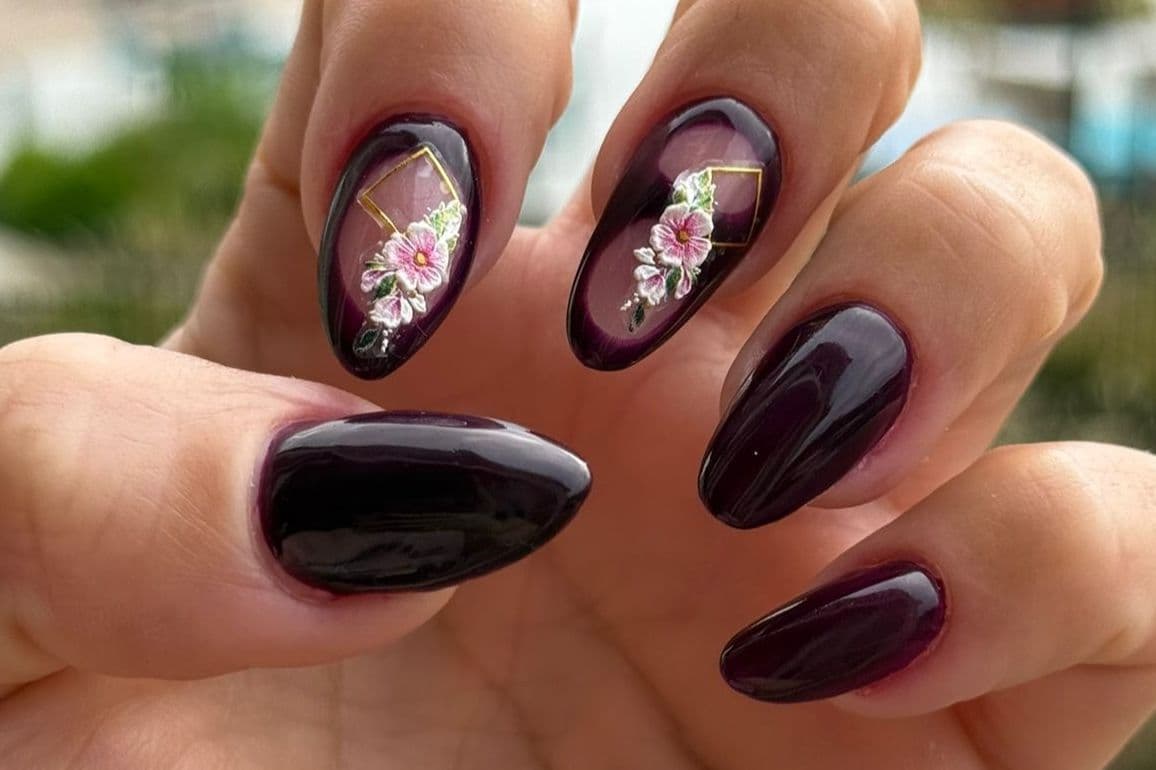 Dark plum almond nails with floral motifs and gold frames
