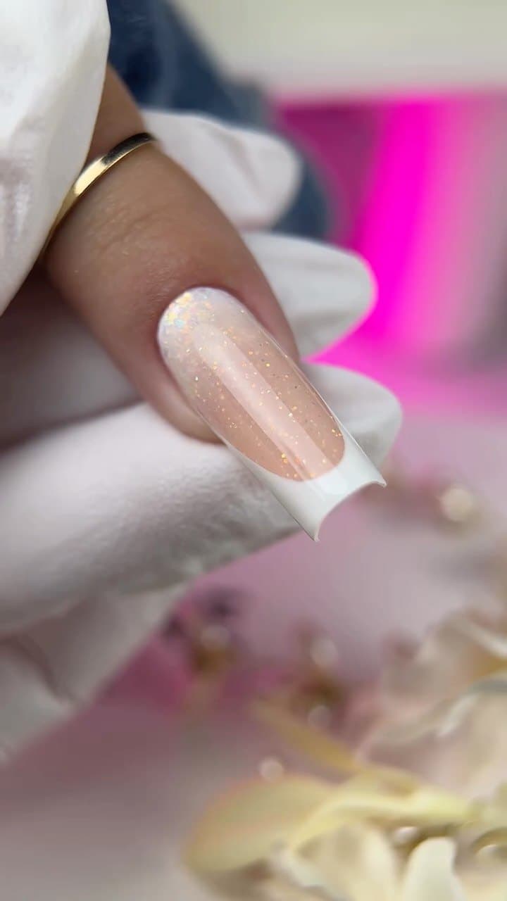 Close-up of a nail with a glitter finish and gold highlights